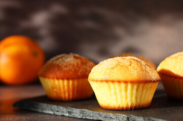 Dessert orange muffins in rows on dark background with orange
