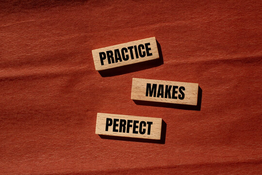 Practice makes perfect words written on wooden blocks with brown background. Conceptual practice makes perfect symbol. Copy space.