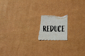 Reduce word written on ripped paper with brown background. Conceptual reduce symbol. Copy space.