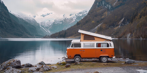 Vintage orange and white van by a fjord in Norway with snow-capped mountains in the background