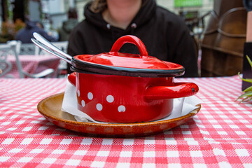 Traditional cabbage soup in the red cast iron pot. The bowl is served on the ceramic plate with...