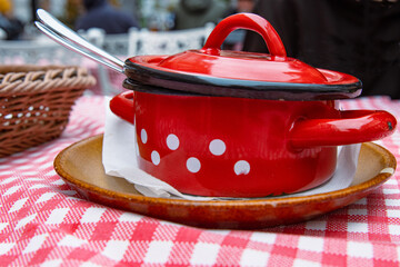 Traditional cabbage soup in the red cast iron pot. The bowl is served on the ceramic plate with...