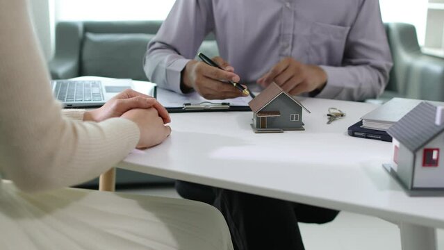 Male real estate agent is negotiating with a female client for a contractual sale of a house.