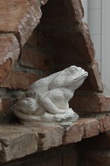 Fototapeta na wymiar Closeup of a white frog sculpture on a brick wall