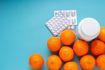 Orange fruits vs pills and medicine top view. Vitamin C close up on blue background with copy...
