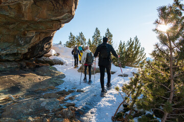 group of hikers crosses a rocky passage on snowshoes