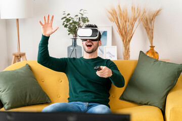 Man using VR AR headset and controller on a yellow sofa