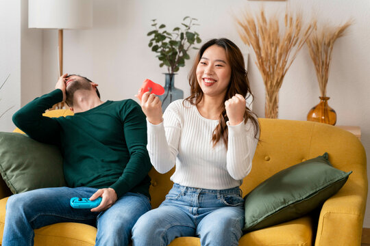 Man and woman enjoying a fun moment with video game controllers on a yellow sofa.