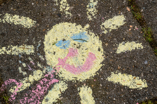 Faded chalk drawing of a sun on pavement.
