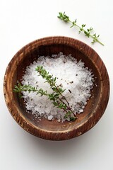 A wooden bowl filled with sea salt and a sprig of thyme. Perfect for culinary or spa concepts