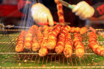 Grilled sausage with the addition of herbs and vegetables on the grill plate, close-up, top view, outdoors. Grilling food, bbq, barbecue