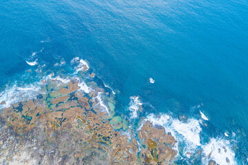 zenithal drone view of sea waves on a rocky shore