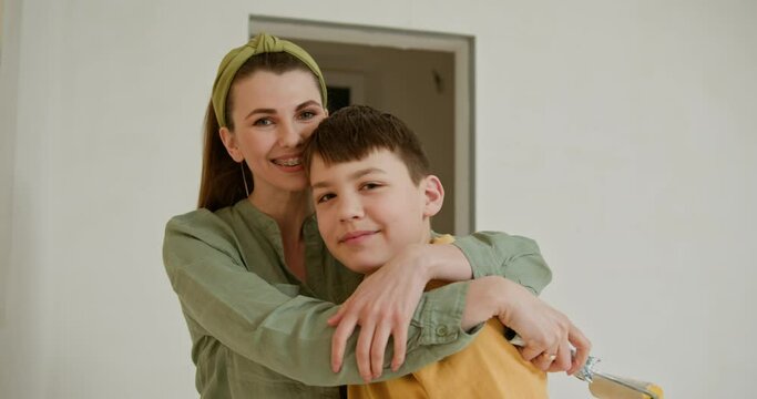 Mother and her young son are busy renovating their new home. With smiles all around, they paint the apartment walls, transforming the space into their own. Creating a personalized living area.