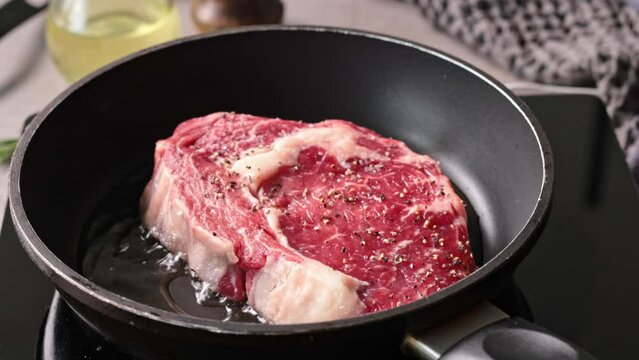 raw steak meat is placed on a pan in heated oil, the process of cooking a steak
