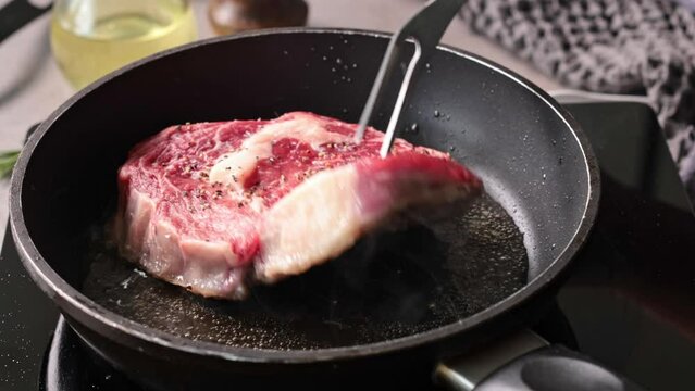 A chef cooks a juicy beef steak on a pan in the kitchen, close-up. The process of making a delicious steak