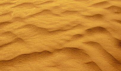 golden yellow desert sand shaped into waves by the wind