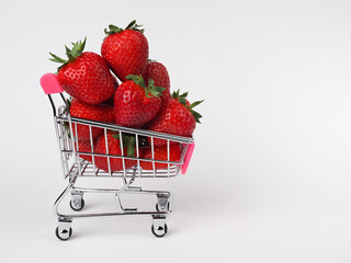small shopping cart with strawberries on white background