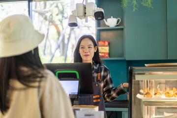 Portrait of asian barista woman small business owner working behind the counter bar and  receive order from customer on coffee packaging and cup of coffee background in cafe or coffee shop