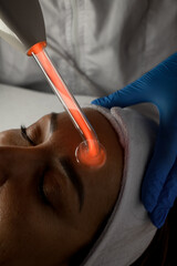 Microcurrent procedure of facial massage for a woman with closes eyes