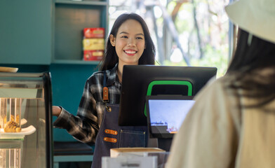 Portrait of asian barista woman small business owner working behind the counter bar and  receive...