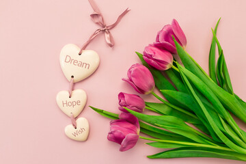 greeting card, banner, pink and purple tulips on a pink background and ceramic hearts with the inscription Dream, Hope, Wish