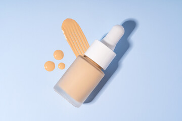 Skincare serum bottle with cream smears on blue background