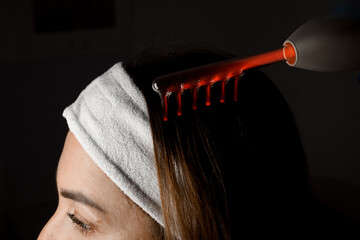 Microcurrent massage of a woman's head on a dark background