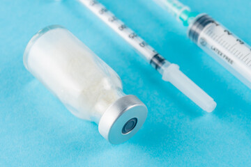 Vaccine vial glass with a syringe on blue background. Medicine vaccination concept. World pandemic...