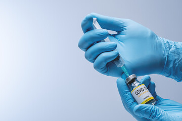 Hands in blue latex gloves with vaccine from glass vial. Healthcare And Medical concept.