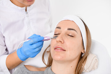 Professional makes a facial procedure for a girl in a gray sweater