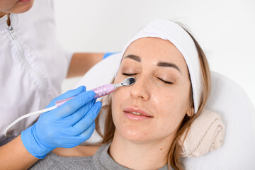 Obraz na płótnie Canvas Cosmetologist makes a microcurrent procedure on a face of a beautiful woman