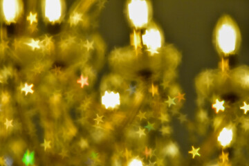 Abstract bokeh effect of the gold, yellow classic crystal lamp with star filter effect on black...