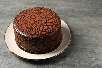 Delicious chocolate truffle cake on grey textured table, space for text