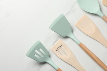 Different spatulas on white marble table, flat lay. Space for text
