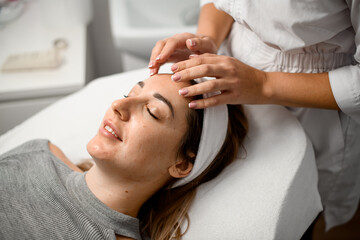 Dermatologist makes a facial massage for a girl with acne with a smile on face - 791700631