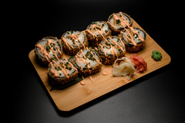 Fried sushi with rice and seafood on a wooden board with ginger and wasabi