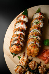 Fried sushi on a big round wooden board with sauce, ginger and hot green wasabi sauce - 791709665