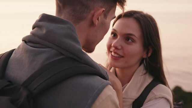 Affectionate young couple in a loving embrace, enjoying a serene sunset on the beach, radiating romance and joy.