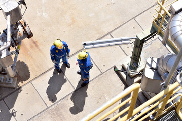 group of industrial workers in work wear in a refinery - oil processing equipment and machinery - 791714466
