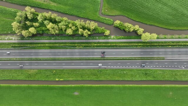 Drone view of a road in the middle of a field. Landscape from a drone. Road and transport. Car traffic. Rows on the field. View from above. 