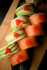 Top view of wrapped sushi decorated with red caviar on a wooden board