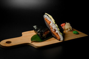 Wrapped in nori rolls stuffed with rice, red fish, avocado on a long green leaf - 791722067