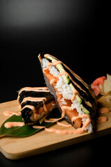 Rolls with white rice, salmon and avocado wrapped in black nori sheets on a wood stand