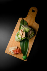 Rolls stuffed with meat or fish fillet wrapped in salad leaf on a wooden stand
