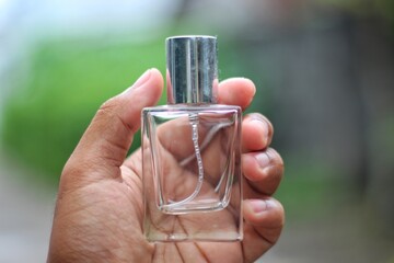 Bottle perfume male hand isolated on blurred background. young man holding bottle of perfume. man...