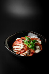 Dark plate with a sliced tomatoes, soft cheese, herbs, spices and soy sauce - 791727899