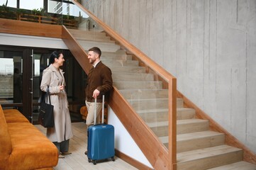 Young couple near reception desk in hotel. Young couple leaving hotel