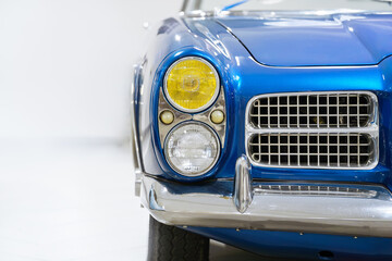 Fototapeta premium Front view of a blue vintage car. Classic car. Headlights. White background.
