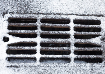 Drain grate covered with snow.