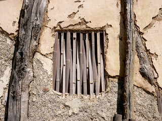 The facade of an old barn made with recycled materials and window closed with bamboo canes